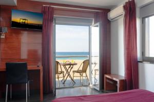 a bedroom with a bed and a desk with a view of the ocean at Hotel Oceano in Nazaré