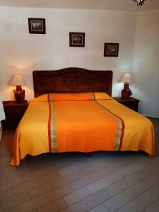 a bed with an orange comforter in a bedroom at Hotel Posada San Javier in Taxco de Alarcón