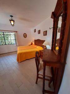 a bedroom with a bed and a desk and a mirror at Hotel Posada San Javier in Taxco de Alarcón