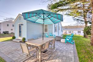 a patio with a wooden table and an umbrella at Cozy Coastal Cottage 5 Mi to Narragansett Beach! in Narragansett