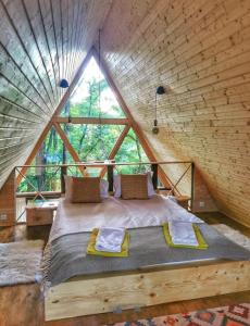 ein Bett in einem Baumhaus mit einem großen Fenster in der Unterkunft Porumbacu Treehouse in Porumbacu de Sus