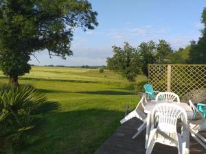 a table and chairs on a deck with a view of a field at Chalet De La Laigne in Allas-Bocage