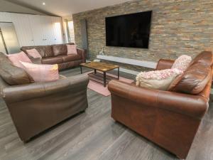 a living room with two leather couches and a tv at Box Tree Escapes in Lancaster