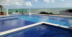 a large swimming pool on top of a building with the ocean at EXCELENTE FLAT 2 QUARTOS no BESSA in João Pessoa