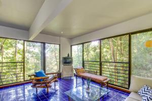 a living room with a couch and a tv and windows at Villa Manuel & The Loft in Quepos