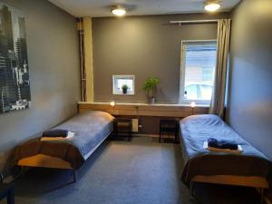 a bedroom with two beds and a desk and a window at Vandrarhem Uppsala - Portalgatan in Uppsala