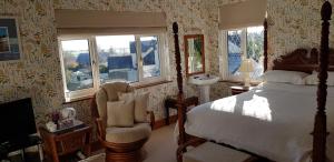 a bedroom with a bed and a chair and windows at Wychwood House in Tenby