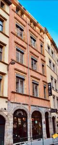 um grande edifício de tijolos com janelas e portas numa rua em Hôtel Le Boulevardier em Lyon