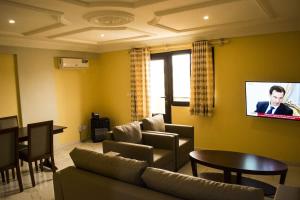 a living room with a couch and a tv on a wall at Hôtel Jouvence International in Yaoundé