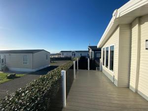 a wooden walkway next to a house at Sea view beach lodge Trecco bay 3 bedroom in Porthcawl