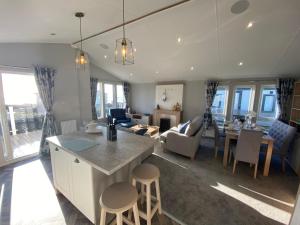 cocina y sala de estar con mesa y sillas en Brand new Sea view beach lodge Trecco bay 3 bedroom, en Porthcawl