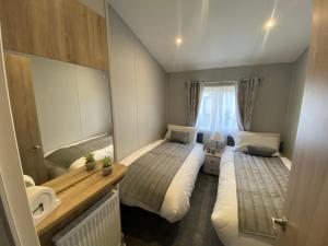 1 dormitorio pequeño con 2 camas y lavamanos en Brand new Sea view beach lodge Trecco bay 3 bedroom, en Porthcawl