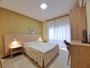 Schlafzimmer mit einem Bett, einem Schreibtisch und einem TV in der Unterkunft Pensión Belmonte II in Benicarló
