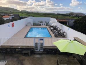 a swimming pool on top of a building with an umbrella at Pôr do Sol in Ribeira Grande