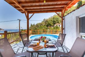 un patio con mesa y sillas junto a una piscina en Villa Watermill, en Skopelos Town