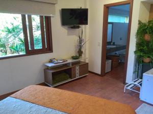ein Wohnzimmer mit einem TV an der Wand in der Unterkunft Bromélia Sabiá & Cia in Teresópolis