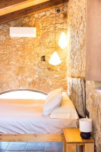 1 dormitorio con 1 cama en una pared de piedra en La Pallissa Pals, en Pals