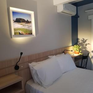 um quarto com uma cama com uma secretária e uma fotografia na parede em Tulipa Hotel em Torres