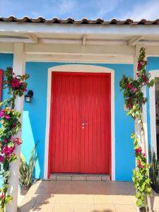 a red door on a blue building with flowers at Pequi hostel in Florianópolis