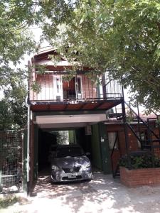 un coche aparcado bajo un edificio con balcón en Ariel Reynoso - Departamento Planta Alta en Mina Clavero