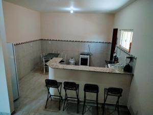 a kitchen with a counter and four stools in a room at Casa em Unamar 3 Cabo Frio RJ in Tamoios