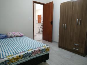 een slaapkamer met een bed en een houten kast bij Casa em Unamar 3 Cabo Frio RJ in Tamoios