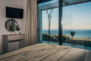 - une chambre avec un lit et une grande fenêtre en verre dans l'établissement Horizon luxury villa, à Agios Nikolaos