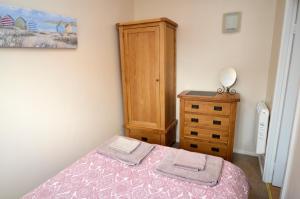 a bedroom with a bed and a wooden dresser at Rockpool Cottage in Beadnell