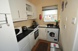 a kitchen with a sink and a washing machine at Rockpool Cottage in Beadnell +3 photos
