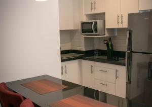 a kitchen with white cabinets and a black counter top at Suites Terraza Imperial in Guatemala +7 photos