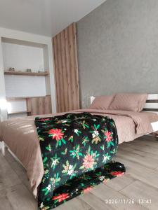 a bed with a black blanket with flowers on it at Дуже файна квартира в самому центрі!!!!Переконайся!! in Rivne