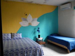 een slaapkamer met een bed en een bloem op de muur bij posada yaxche in Xul-Ha