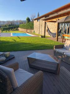 un patio con sillas de mimbre, mesa y piscina en Quinta do Ovelheiro, en Guimarães