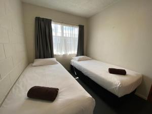 two beds in a small room with a window at Ulster Apartments in Hamilton