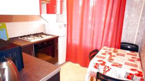 - une cuisine avec un rideau rouge, une table et une cuisinière dans l'établissement Apartment Perevedenovskiy, à Moscou