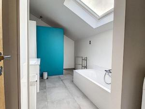 La salle de bains est pourvue d'un mur bleu et d'une baignoire. dans l'établissement Classy Holiday Home in Achet with Garden, 