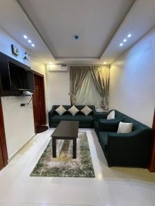 uma sala de estar com um sofá verde e uma mesa em ابيات ميرا em Abha