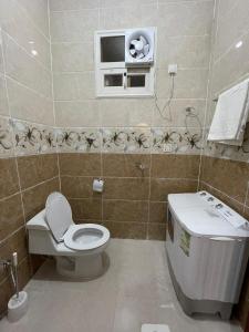 a bathroom with a toilet and a sink and a window at ابيات ميرا in Abha