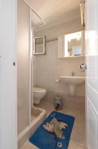 y baño con aseo, lavabo y alfombra azul. en Hotel Klonos - Kyriakos Klonos, en Aegina Town