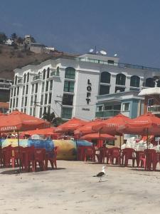 a building with tables and chairs and red umbrellas at LOFT NA PRAINHA EM Arraial do Cabo in Arraial do Cabo