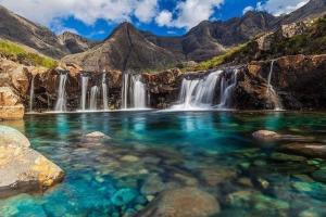 a pool of water in front of a waterfall at Loch Eyre Shepherd Hut in Portree