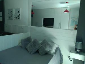 1 dormitorio con cama con almohadas y espejo en LOFT NA PRAINHA EM Arraial do Cabo, en Arraial do Cabo