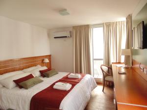 a hotel room with a bed and a desk and a window at Catamarca Suites Land in Rosario