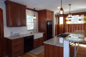 a kitchen with wooden cabinets and a black refrigerator at Winnisquam Lake House in Tilton