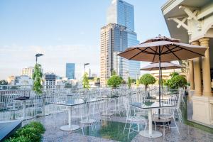 eine Reihe von Tischen und Stühlen mit einem Sonnenschirm in der Unterkunft Rex Hotel in Ho-Chi-Minh-Stadt