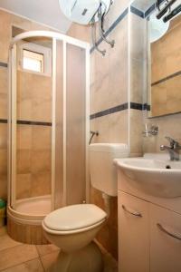 La salle de bains est pourvue de toilettes, d'un lavabo et d'une douche. dans l'établissement Apartments and rooms Cherry - relax & chill by the pool, à Novalja