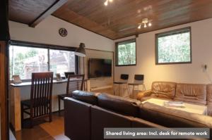 a living room with a brown couch and a kitchen at Guest House Preta Torami in Ichinomiya