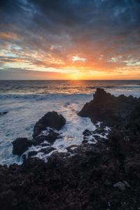 a sunset over the ocean with rocks in the water at Apartamentos con vistas al mar en El Remo in Los Llanos de Aridane