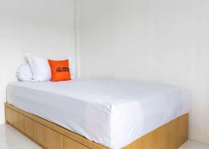 ein weißes Bett mit zwei orangefarbenen Kissen darauf in der Unterkunft KoolKost near Wisata Purwahamba Indah Tegal in Tegal