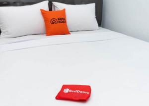 ein Bett mit weißen Kissen und einer roten Tasche darauf in der Unterkunft KoolKost near Wisata Purwahamba Indah Tegal in Tegal